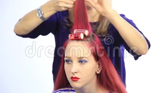 女造型师为年轻的红头发妇女创造了一个大卷发的完美发型视频的预览图