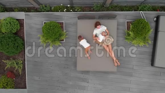 空中年轻的母亲和她的小儿子兄弟在他们的花园空闲时间家庭价值观温暖的颜色视频的预览图