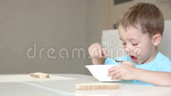 孩子坐在厨房的桌子旁吃汤健康宝宝食品的概念摄像机滑块移动视频的预览图