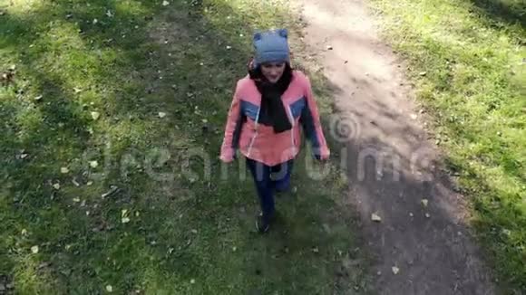 秋天公园里一位年轻的美女在树上散步空中拍摄无人机的视频视频的预览图