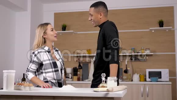 不同种族的夫妻在厨房玩着向对方扔面粉视频的预览图