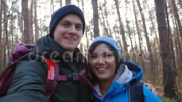 徒步旅行和背包概念年轻的幸福夫妇带着背包在森林里自拍视频的预览图