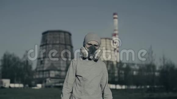 戴着污染面具的小男孩对着工厂的烟囱空气污染概念戴着灰色杯子和呼吸器的孩子视频的预览图