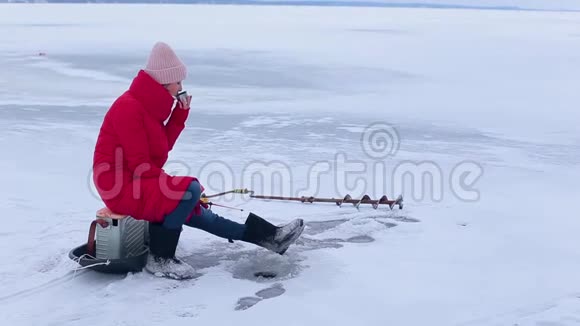 穿着红色温暖夹克和毛毡靴的漂亮渔夫在冰冻的河上帮助钓鱼视频的预览图