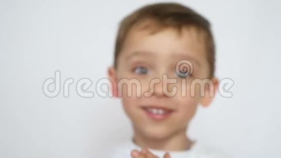 一个快乐的孩子微笑着把他的手放在镜头前视频的预览图