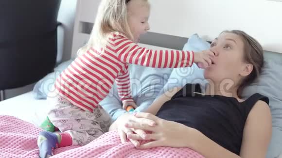 妈妈和女儿扮演医生一个女人躺在床上躺在毯子下面视频的预览图
