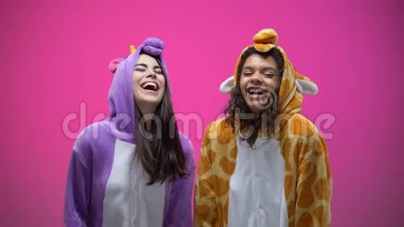 穿着独角兽和长颈鹿睡衣的有趣的年轻女人笑着娱乐视频的预览图