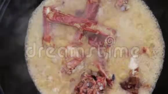 街头美食炖排骨放在酱油里洋葱在火炭火和大锅里煮视频的预览图