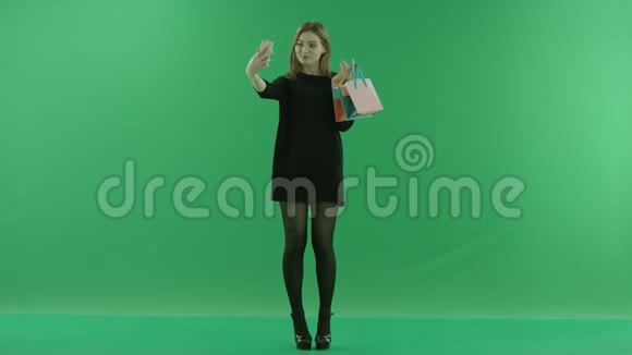 漂亮的年轻女士用智能手机上的礼物包自拍彩色钥匙绿色背景视频的预览图