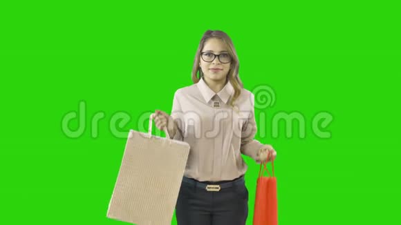 年轻女性购物狂在一个孤立的绿色背景下购物的喜悦视频的预览图