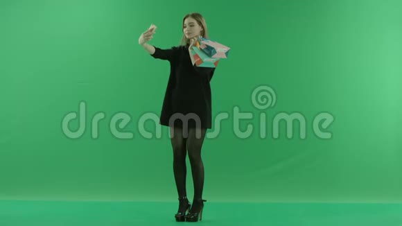 漂亮的年轻女人带着礼物包拍照彩色钥匙绿色背景视频的预览图