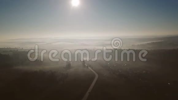 汽车正行驶在乡村道路上雾中的风景美丽的大自然录像片段高空俯视图视频的预览图