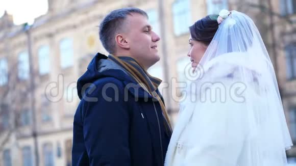 冬季婚礼新婚夫妇穿着婚纱新郎轻轻吻新娘的额头拥抱他们很高兴视频的预览图