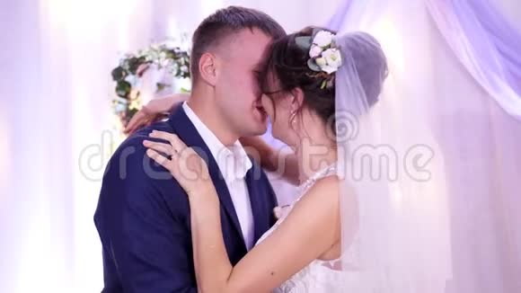 美丽幸福相爱的新婚夫妇穿着婚纱在婚礼上接吻拥抱吻新娘视频的预览图