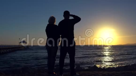 一对浪漫的情侣站在那里看海洋日落视频的预览图