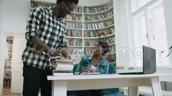 非洲男孩走到图书馆给五个有吸引力的非洲女孩并开始一起在图书馆学习视频的预览图