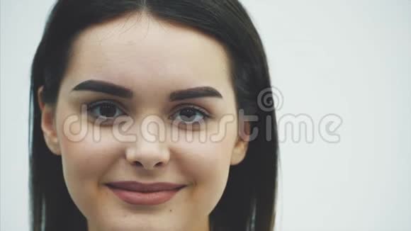 一个美丽的年轻女孩皮肤光滑是一个轻盈的背景自然化妆和卷曲的黑发在这段时间里视频的预览图
