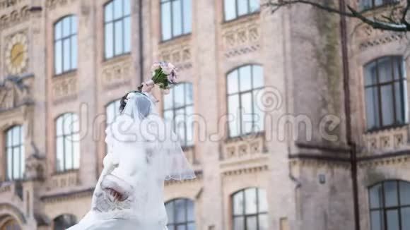 美丽新娘的肖像穿着白色连衣裙面纱和毛皮外套新娘在旋转开心地笑着手里拿着一个视频的预览图