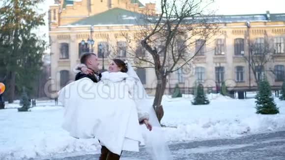 冬季婚礼新婚夫妇穿着婚纱新郎把新娘抱在怀里旋转着他们开心微笑着视频的预览图
