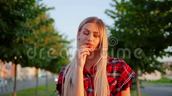 肖像可爱的女孩留着白色长发穿着红色格子衬衫是怀疑和盯着相机视频的预览图