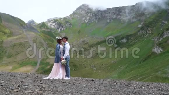 新郎和新娘站在远处奇妙的青山峰前华丽的户外婚礼视频的预览图