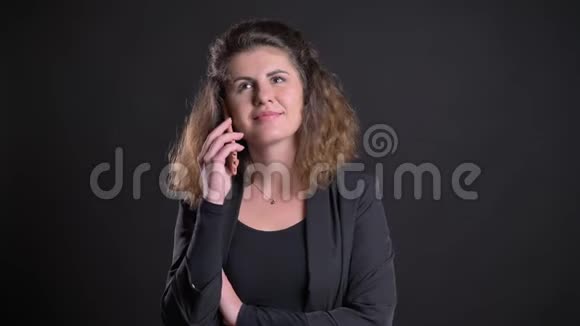 超重的高加索女人在黑色背景下用手机微笑交谈的特写照片视频的预览图