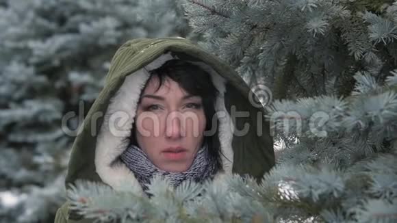 伤心的女人在冬天的森林里摆姿势躲在杉树枝后面视频的预览图