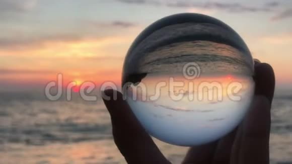 女子双手捧着水晶球在美丽的海滩日落视频的预览图