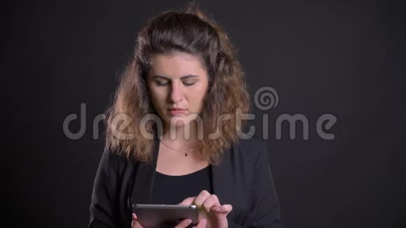 集中超重的白种人妇女在平板电脑上工作的特写照片显示了黑色背景下的绿色屏幕视频的预览图