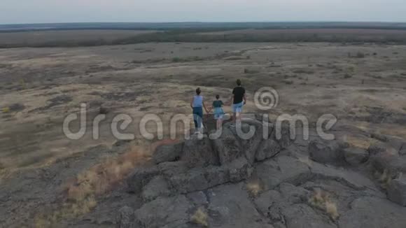 空中观景一家人站在山上母亲父亲和儿子去山里远足日落视频的预览图