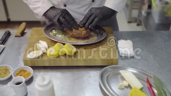 厨师双手戴黑色乳胶手套在金属盘子里摩擦一块小牛肉腌制肉带厨房的桌子视频的预览图
