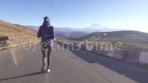 年轻的穆斯林妇女戴着头巾在山路上奔跑阳光灿烂后视慢悠悠视频的预览图
