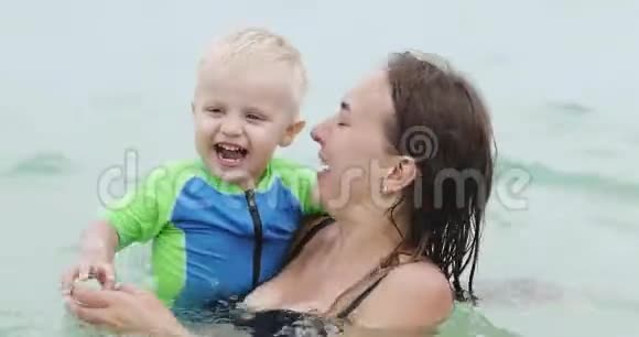 一个快乐的母亲和一个小孩子在海里玩得很开心视频的预览图
