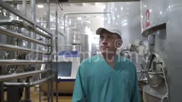 食品厂工人在现代日记厂行走在设备和监控生产之间牛奶加工线视频的预览图
