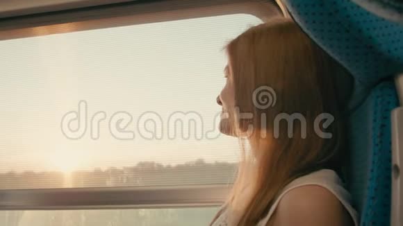 女人在日落时看着窗外然后坐火车去相机旅行视频的预览图