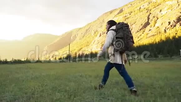 徒步旅行者背包族女孩走在绿色的田野上视频的预览图