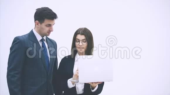 年轻的商务夫妇站着看着笔记本电脑里的东西讨论着重要的问题思考着视频的预览图