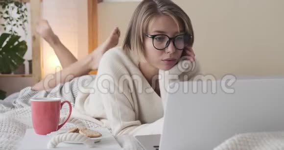女人用笔记本电脑在床上吃饼干视频的预览图