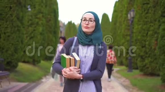 戴头巾的阿拉伯学生带着书去公园学习视频的预览图