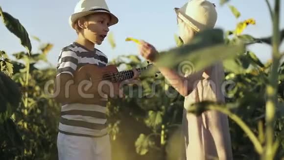 孩子们在田野里玩向日葵快乐男孩玩四弦琴视频的预览图