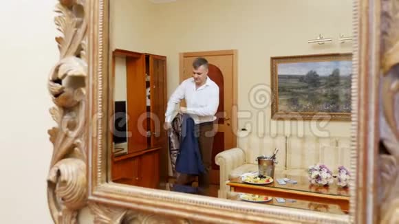 在一面美丽的大镜子里一个年轻英俊的男人一个商人穿上夹克为一个视频的预览图