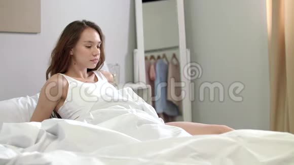 年轻女子早上在床上触摸身体皮肤快乐女人摸腿视频的预览图