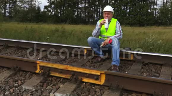 铁路工人坐在铁轨上喝咖啡视频的预览图