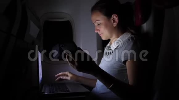 有智能手机的女商人在窗户附近的飞机上工作视频的预览图