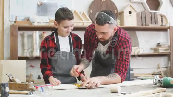 爸爸正在帮儿子用尺子在木板上刻线视频的预览图