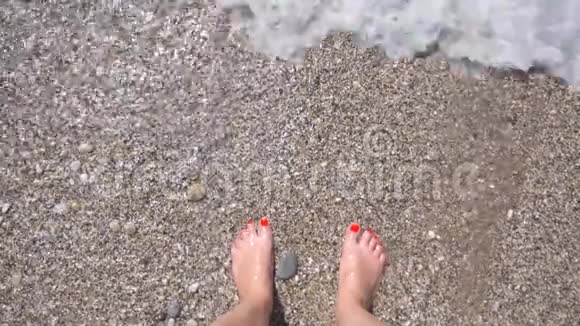 海浪冲刷着纤细的女性脚无法辨认的女人站在鹅卵石滩上享受着温暖的大海视频的预览图