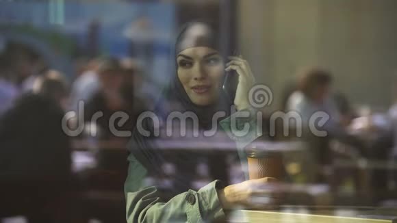 迷人的阿拉伯年轻女性在电话中交谈在咖啡馆里度过空闲时间放松一下视频的预览图
