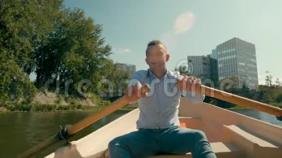 穿着衬衫的领队是夏天在城市河流上划桨和划艇视频的预览图
