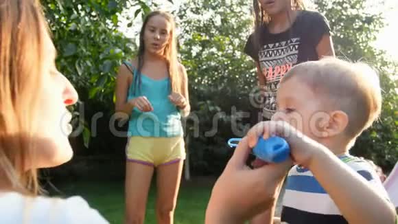 4K慢动作视频快乐家庭与孩子吹肥皂泡在后院花园温暖的晴天视频的预览图