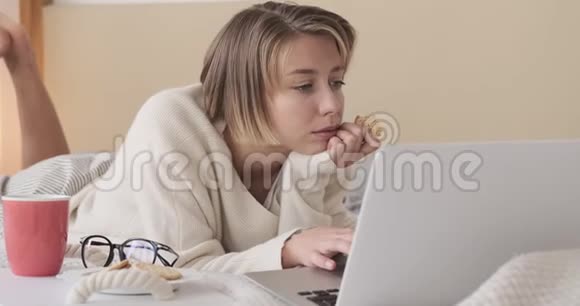 女人用笔记本电脑在床上吃饼干视频的预览图
